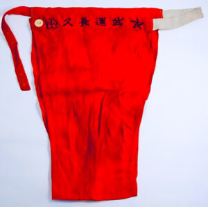 A vermillion red fundoshi with Japanese katakana and a star. The fundoshi is etchu-style, with a button for ease-of-use.
