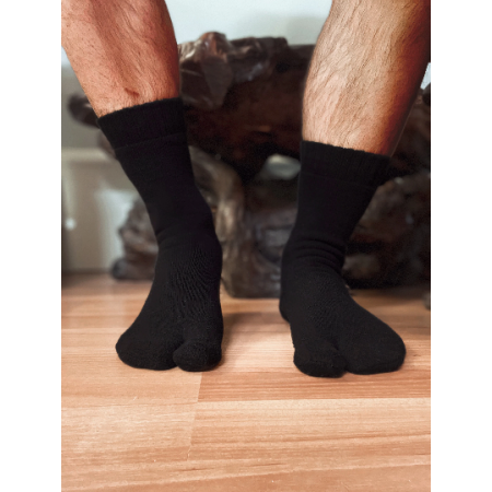 A man's semi-hairy legs with feet in tabi socks (Japanese traditional flip-flop socks) on a wood floor.